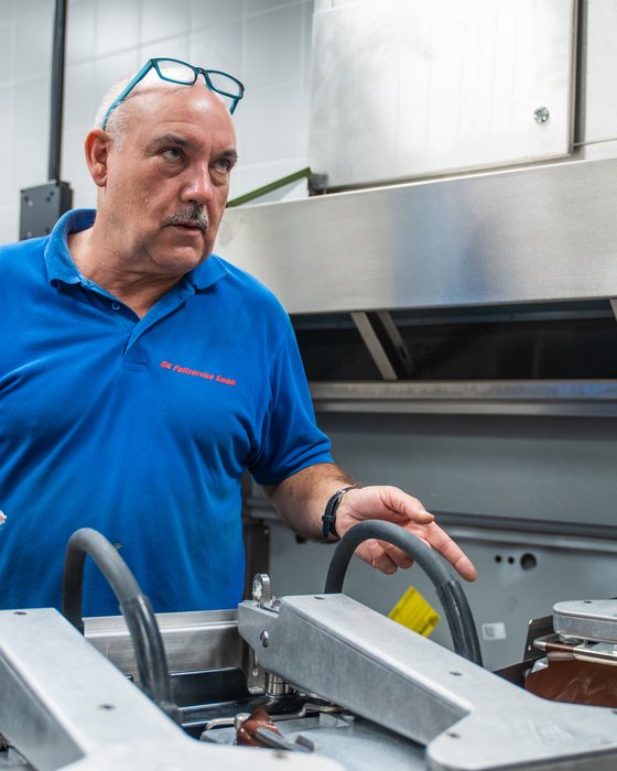 Servicetechniker der GK Fullservice an einem Küchengerät unter der Abzugshaube